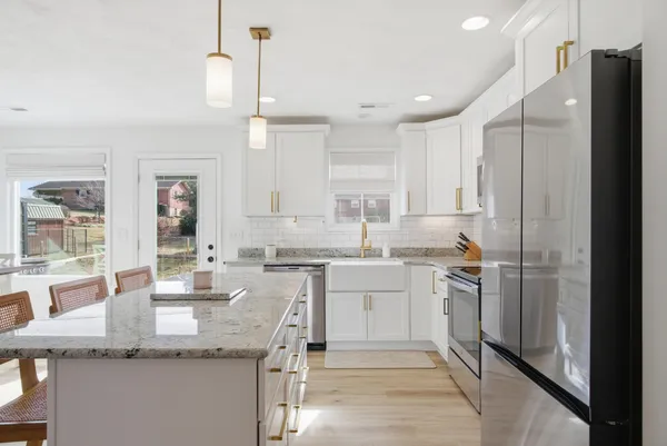 a kitchen with stainless steel appliances granite countertop a sink a stove a refrigerator and island with wooden floor