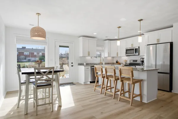 a kitchen with stainless steel appliances granite countertop a stove refrigerator and a dining table with wooden floor