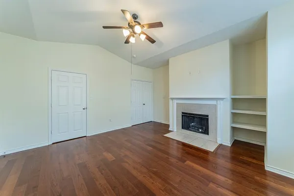 a view of an empty room with wooden floor fireplace and a window