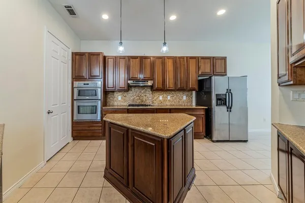 a kitchen with stainless steel appliances granite countertop a refrigerator a sink and a stove