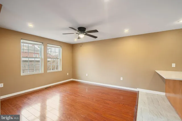 a view of an empty room with a window and wooden floor
