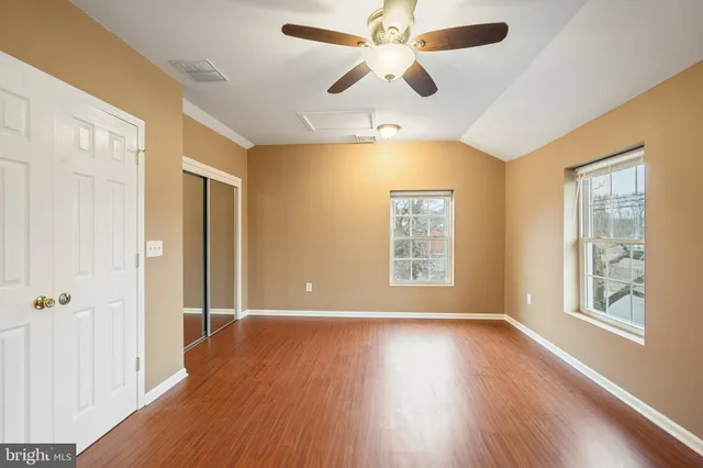 a view of an empty room with a window and wooden floor