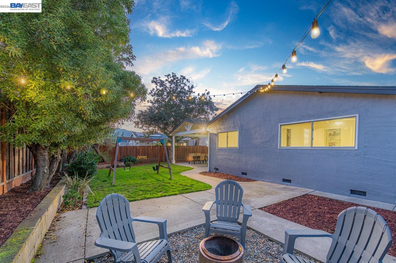 a view of a backyard with table and chairs with wooden fence and plants