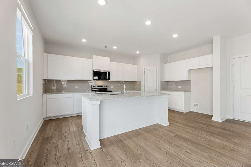 5420 Aurora Trail Flowery Branch, GA 30542 - Photo 13 of 38 a kitchen with granite countertop white cabinets and wooden floor