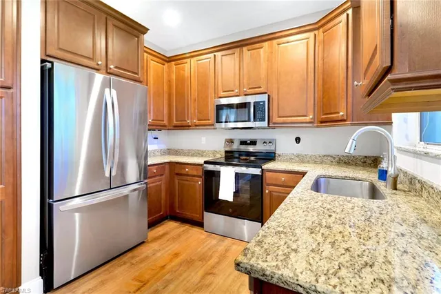 a kitchen with stainless steel appliances granite countertop a refrigerator a stove top oven a sink and dishwasher