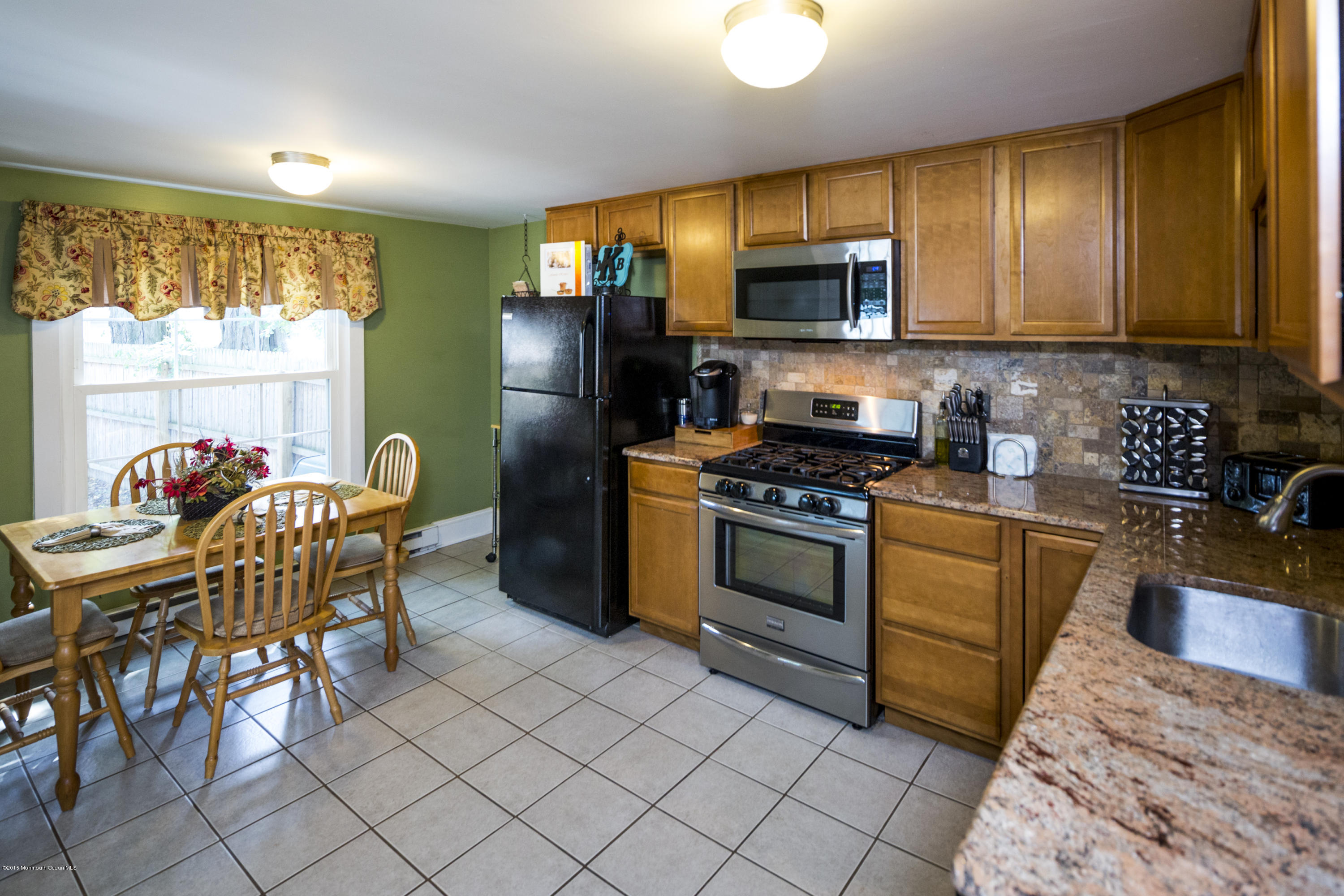 167 Newman Springs Road Tinton Falls, NJ 07724 - Photo 10 of 23 a kitchen with stainless steel appliances granite countertop a stove a sink a microwave a dining table and chairs with wooden floor