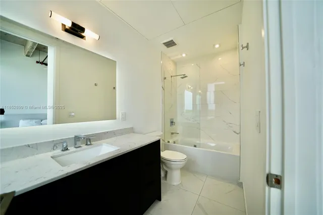a bathroom with a double vanity sink toilet mirror and shower