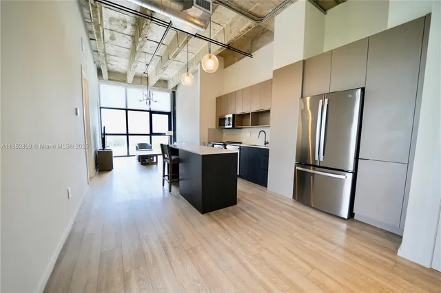 a kitchen with stainless steel appliances a refrigerator a sink dishwasher a stove top oven a dining table and chairs with wooden floor