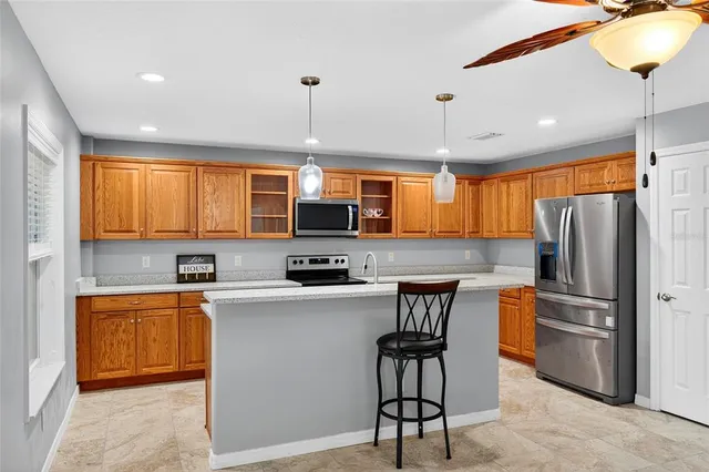 a kitchen with stainless steel appliances granite countertop a refrigerator a sink dishwasher a stove top oven a dining table and chairs with wooden floor