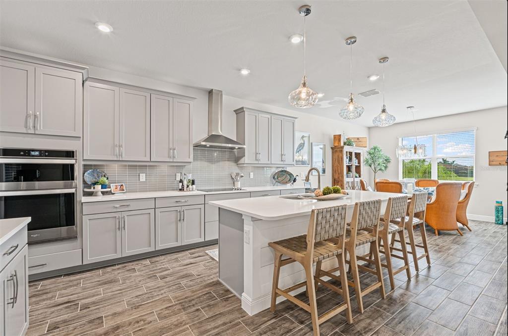 20380 Symphony Place Venice, FL 34293 - Photo 11 of 56 a kitchen with stainless steel appliances kitchen island granite countertop a table chairs sink and cabinets