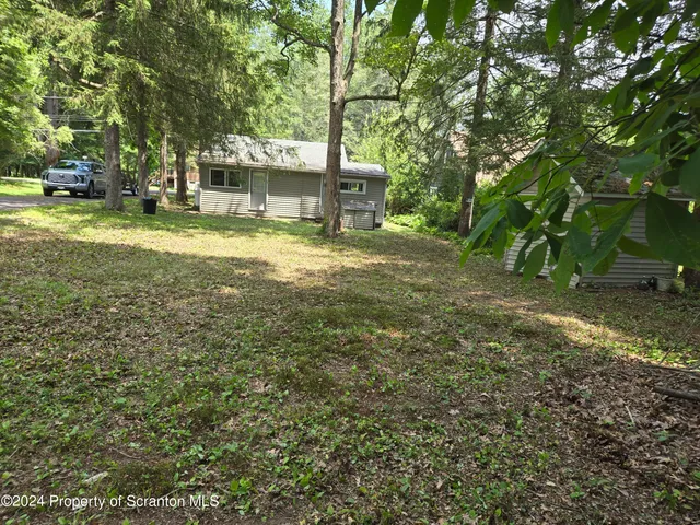 a view of a house with a big yard and large trees