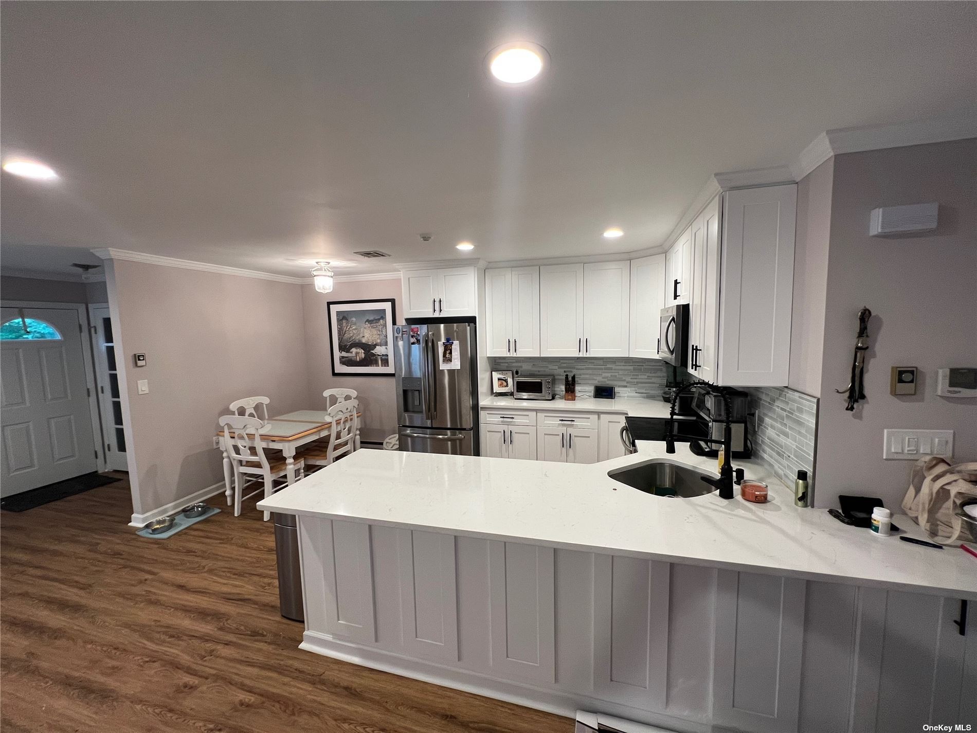 a room with stainless steel appliances kitchen island granite countertop a refrigerator and a sink