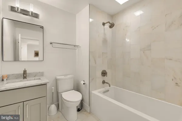a bathroom with a toilet a sink a mirror a bathtub and vanity