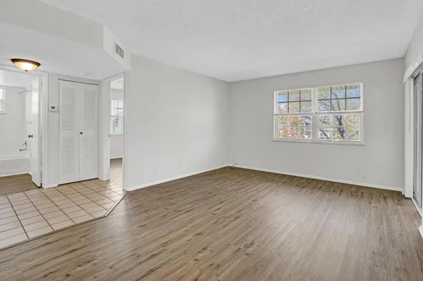 a view of an empty room with wooden floor and a window