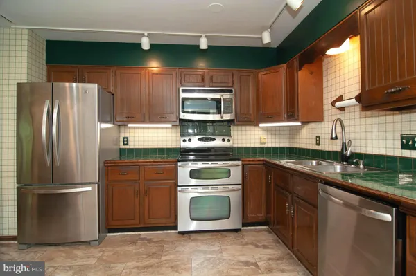 a kitchen with granite countertop a refrigerator stove top oven and sink
