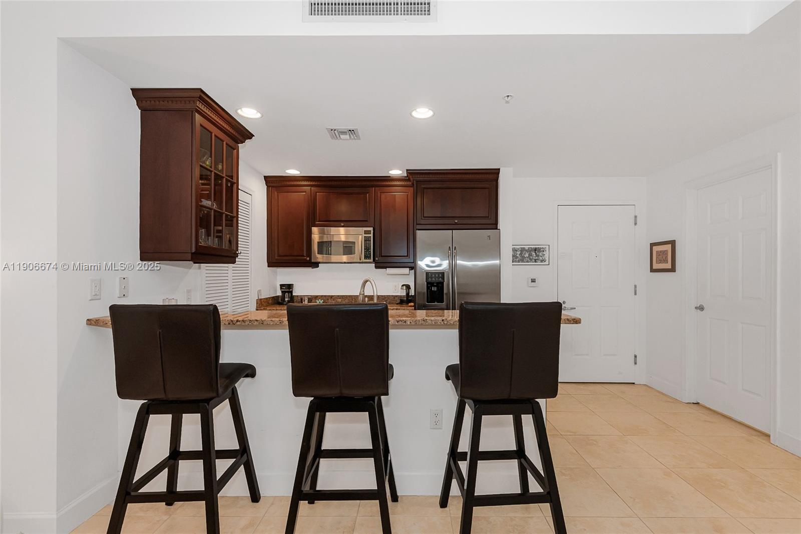 100 Andalusia Avenue, Unit 210 Coral Gables, FL 33134 - Photo 9 of 29 a kitchen with stainless steel appliances kitchen island granite countertop a refrigerator and a stove top oven