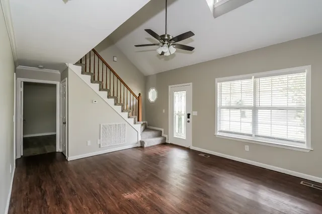 a view of empty room with wooden floor and fan