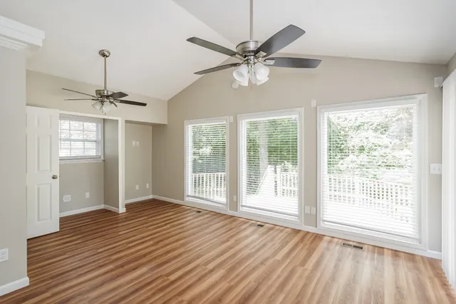 a view of an empty room with a window and wooden floor