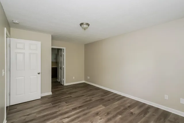 a view of an empty room with wooden floor and closet