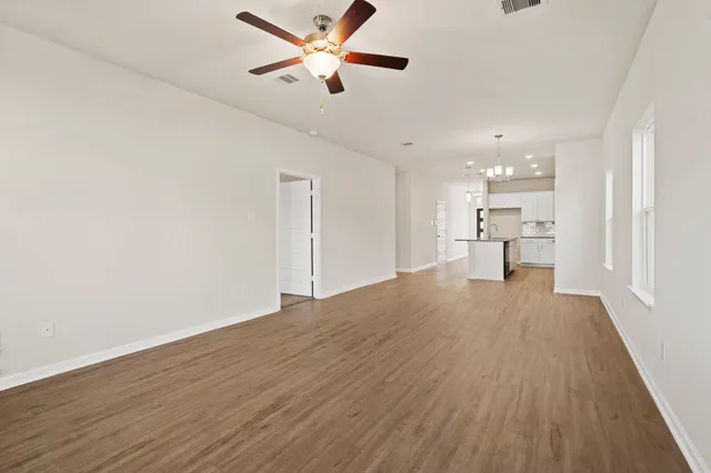 a view of empty room with wooden floor and a ceiling fan