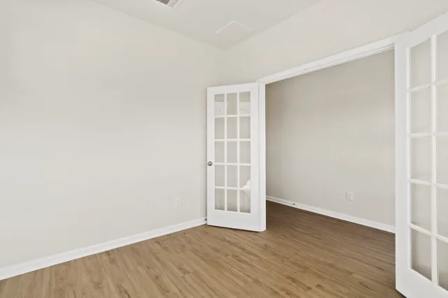 an empty room with wooden floor and windows