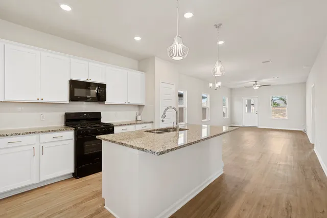 a large kitchen with stainless steel appliances granite countertop a stove a sink and a microwave