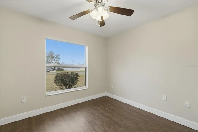 an empty room with a window and ceiling fan
