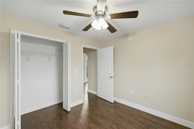 an empty room with wooden floor ceiling fan and windows