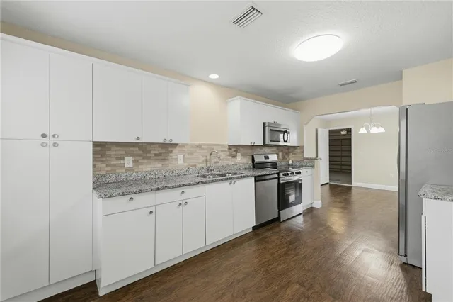 a kitchen with stainless steel appliances granite countertop a stove top oven a sink and white cabinets
