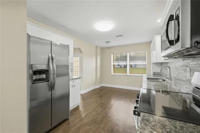 a kitchen with stainless steel appliances granite countertop a refrigerator a stove and a sink with wooden floor