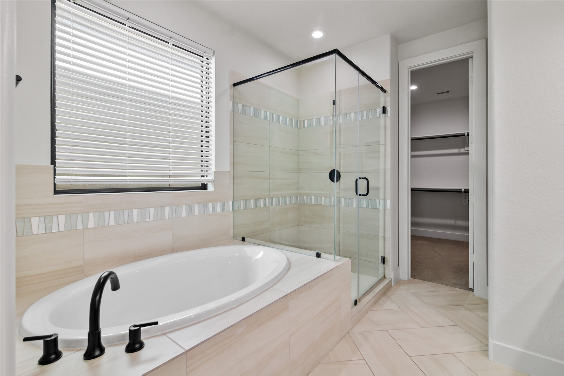 4231 Allen Street Houston, TX 77007 - Photo 27 of 31 This primary bathroom features a spa-inspired design with a separate soaking tub and a modern glass-enclosed shower. The space is tied together by warm, neutral tones and bold black accents.