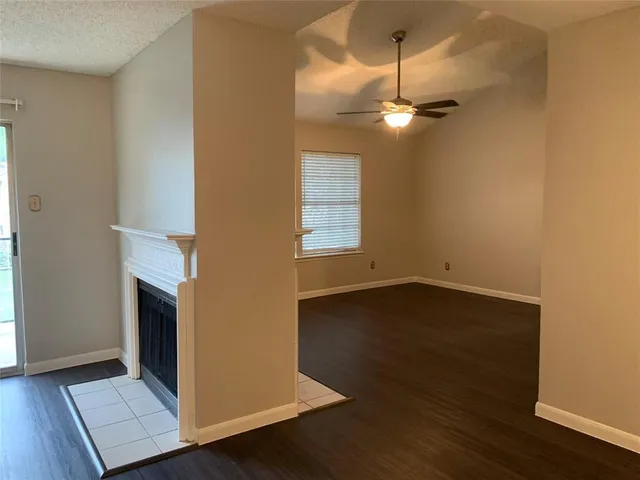 a view of an empty room with wooden floor and a fireplace
