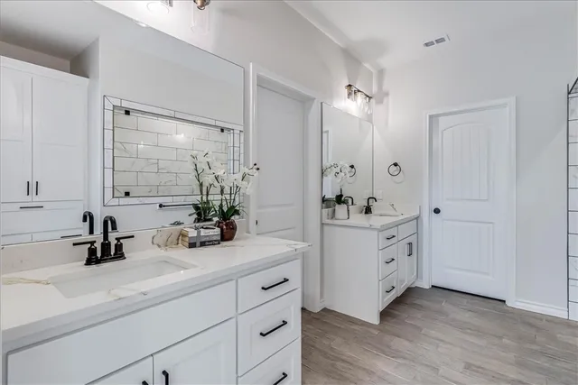 a bathroom with a double vanity sink mirror and next to a white cabinet