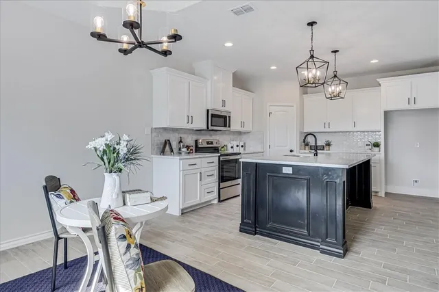 a kitchen with kitchen island granite countertop a sink a center island stainless steel appliances and cabinets