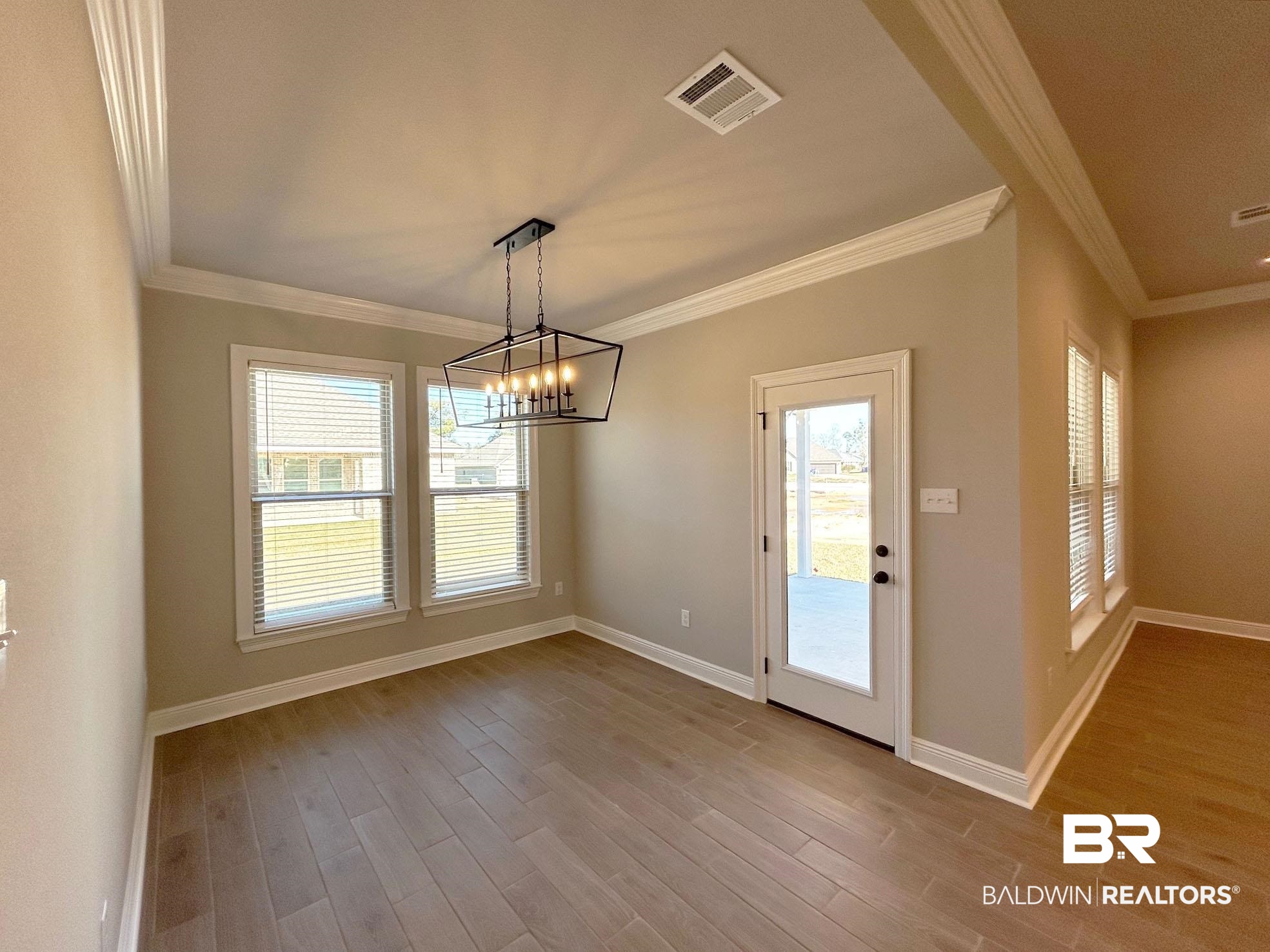 877 Sumter Loop Foley, AL 36535 - Photo 5 of 18 Unfurnished dining area featuring crown molding, wood finished floors, visible vents, and baseboards