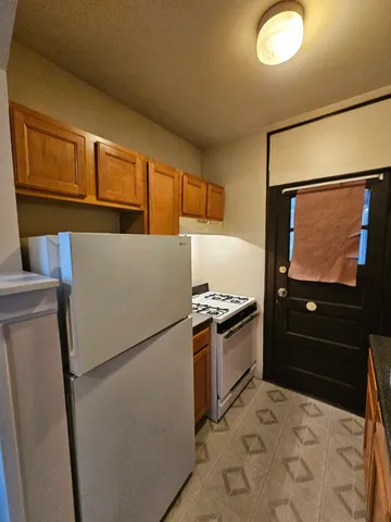 a kitchen with granite countertop a refrigerator and a stove top oven
