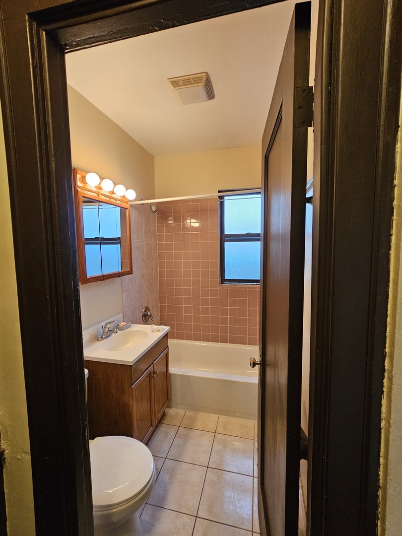 121 West 80th Street, Unit 2E Chicago, IL 60620 - Photo 6 of 7 a bathroom with a sink a toilet a mirror and shower