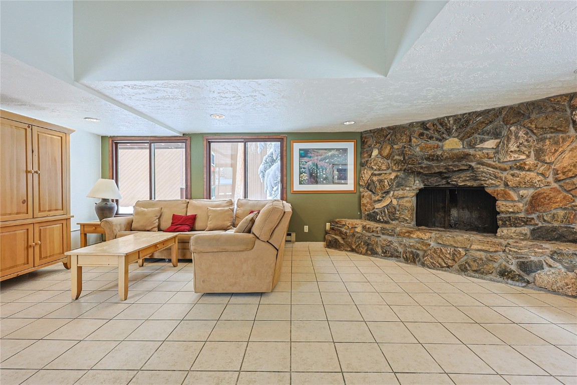 373 Wild Irishman Road, Unit 1071 Keystone, CO 80435 - Photo 22 of 22 Living room featuring a textured ceiling, light tile patterned floors, and a stone fireplace