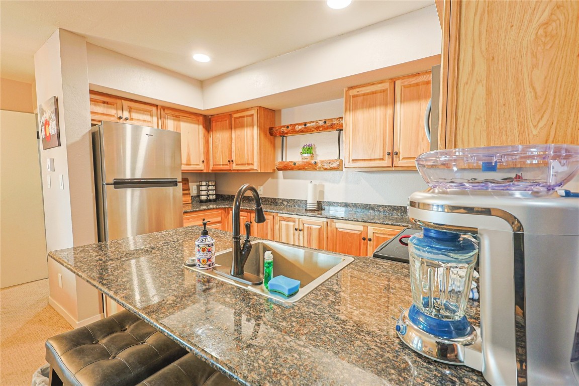 373 Wild Irishman Road, Unit 1071 Keystone, CO 80435 - Photo 6 of 22 Kitchen with freestanding refrigerator, a breakfast bar area, open shelves, a peninsula, and dark stone counters