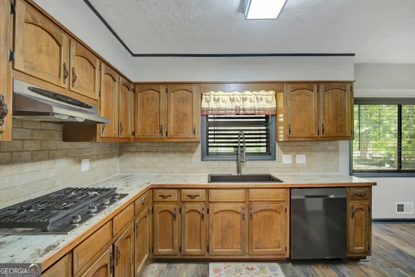 a kitchen with stainless steel appliances granite countertop a sink a stove and cabinets
