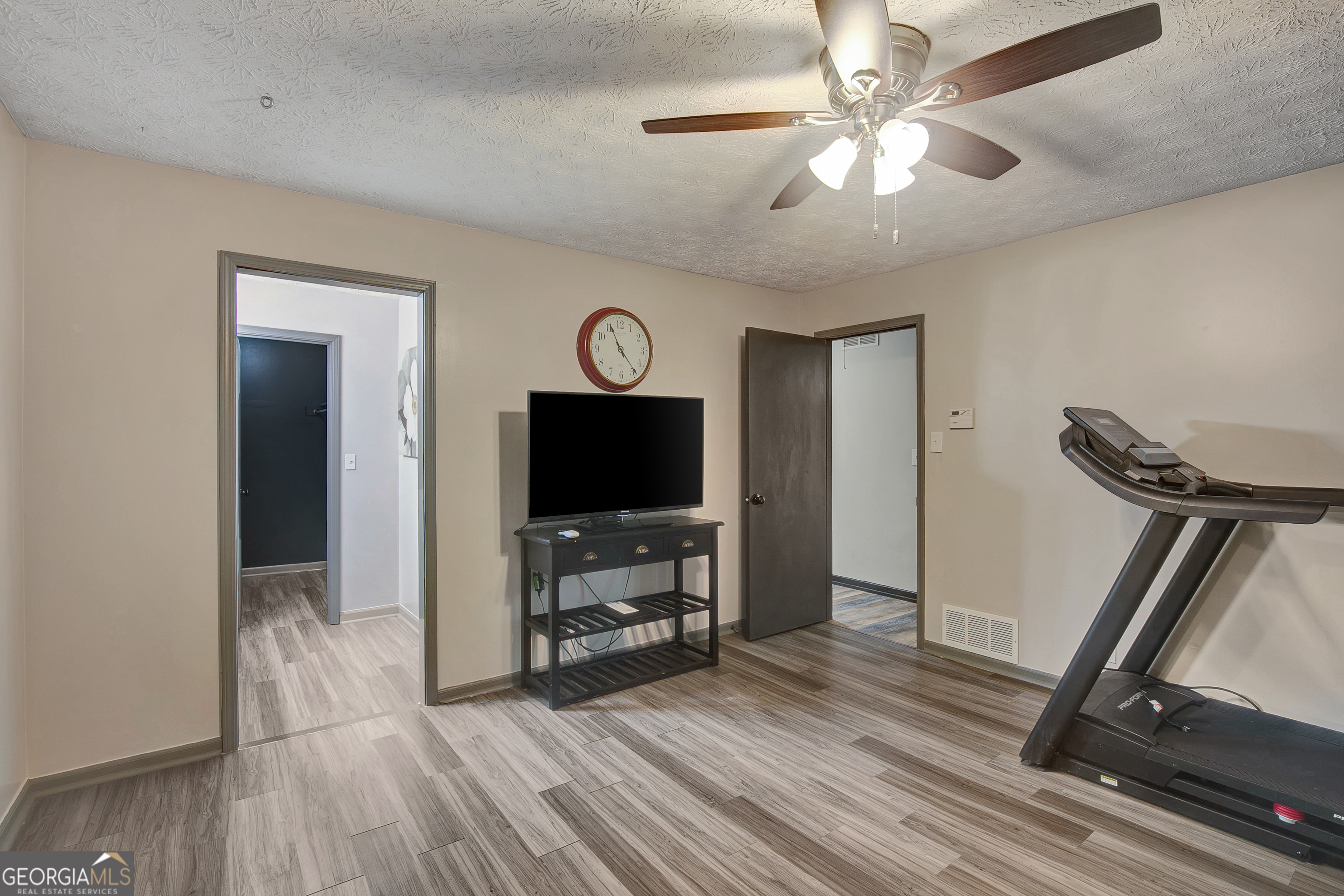 1188 Raymond Hill Road Newnan, GA 30265 - Photo 22 of 47 a view of a livingroom with a flat screen tv wooden floor and a ceiling fan