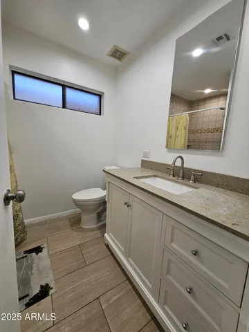 a bathroom with a granite countertop toilet sink and mirror