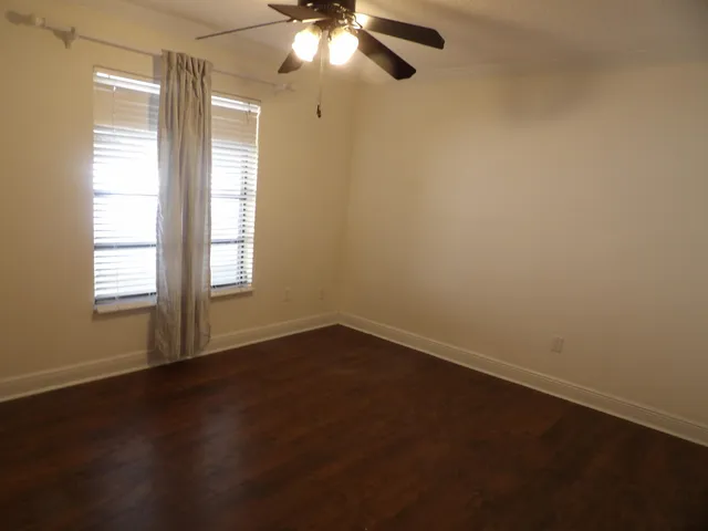 an empty room with a window and a fan
