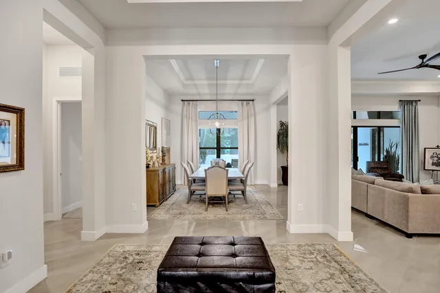 a kitchen with stainless steel appliances kitchen island granite countertop a dining table chairs and a refrigerator