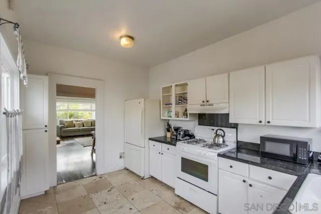 a kitchen with granite countertop a sink stove and cabinets