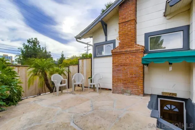 a view of a white house with large windows and table and chairs