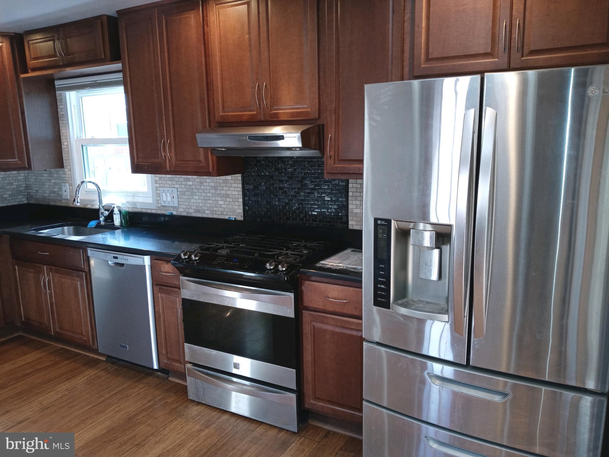 12616 Epping Road Silver Spring, MD 20906 - Photo 6 of 28 a kitchen with granite countertop stainless steel appliances and wooden cabinets