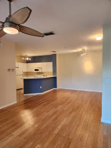 a view of kitchen and empty room with wooden floor
