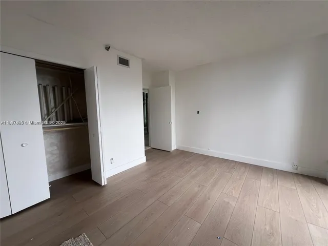 an empty room with wooden floor and closet