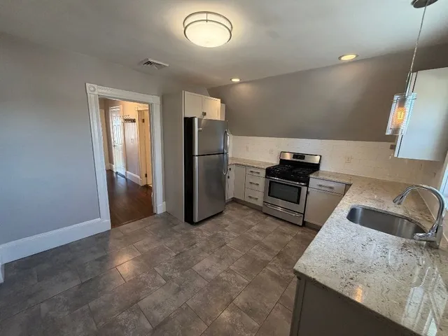 a kitchen with stainless steel appliances granite countertop a sink a stove and a refrigerator